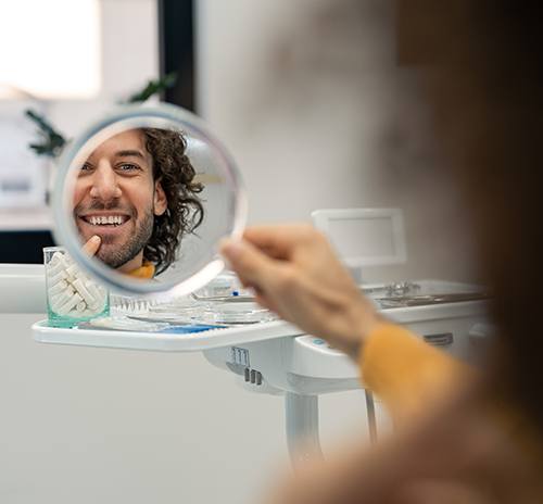 Man looking at his new smile in the mirror